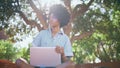 Curly teenager sitting laptop at sunlight looking around. African girl relaxing Royalty Free Stock Photo