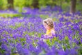 Curly toddler girl in bluebell flowers in spring forest Royalty Free Stock Photo