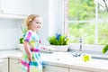 Curly toddler girl in colorful dress washing dishes Royalty Free Stock Photo