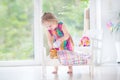 Curly toddler girl feeding her toy bear in white crib pla Royalty Free Stock Photo