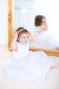 Curly toddler girl trying on white dress next mirror Royalty Free Stock Photo