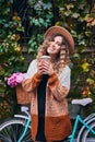 Curly woman against bicycle parked to wall covered with ivy. Royalty Free Stock Photo