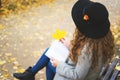 Woman in hat with book is sitting in autumn park. Royalty Free Stock Photo