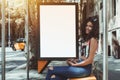 Curly woman on bus stop with empty billboard template behind Royalty Free Stock Photo