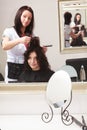 Curly woman looking at mirror by hairstylist. In hairdressing salon. Royalty Free Stock Photo