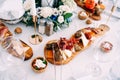 Curly wooden cutting board with slices of black bread, prosciutto and cheese near a salt shaker with a pepper shaker.