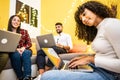 Curly young Afro-American black hispanic girl typing on her notebook at home sitting on the ground with her group of university Royalty Free Stock Photo