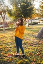 Curly young girl in yellow sweater on grass with autumn bouquet of dry leaves and flowers Royalty Free Stock Photo