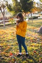 Curly young girl in yellow sweater on grass with autumn bouquet of dry leaves and flowers Royalty Free Stock Photo