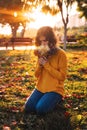 Curly young girl in yellow sweater on grass with autumn bouquet of dry leaves and flowers Royalty Free Stock Photo