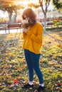 Curly young girl in yellow sweater on grass with autumn bouquet of dry leaves and flowers Royalty Free Stock Photo