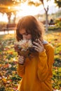 Curly young girl in yellow sweater on grass with autumn bouquet of dry leaves and flowers Royalty Free Stock Photo