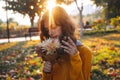 Curly young girl in yellow sweater on grass with autumn bouquet of dry leaves and flowers Royalty Free Stock Photo