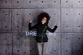 Curly young woman with flying hair actively posing on the background of concrete wall. A colored illuminated Dream big.