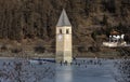 CURON VENOSTA, 06 January 2023: Tourists walk on the frozen lake of Resia. It is an artificial reservoir in the west of South