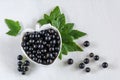 Currant berries in a white berry-shaped plate on a white wooden background