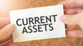 CURRENT ASSETS word inscription on white card paper sheet in hands of a businessman. recap concept. red and white paper