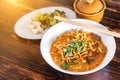 Curried noodle soup Khao soi with beef and spicy coconut milk on wood table. Royalty Free Stock Photo