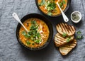 Curried red lentil tomato and coconut soup - delicious vegetarian food on grey background, top view. Flat lay