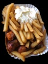 Currywurst & Pommes on black background: Famous German Fast Food Curry Sausage with French Fries and Curry Sauce Royalty Free Stock Photo