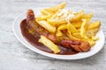 Currywurst, sausage with curry ketchup, a popular fast food in Germany, served with French fries and mayonnaise on an oval plate Royalty Free Stock Photo