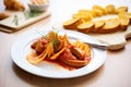 currywurst sliced on a white plate with a side of bread