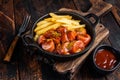Currywurst street food meal, Curry spice on wursts served French fries in a pan. Dark wooden background. Top view