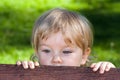 A curuos little boy hiding behind a bench Royalty Free Stock Photo