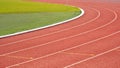 Curve lines pattern background of red synthetic running tracks and green field in athletic outdoors stadium Royalty Free Stock Photo