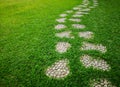 Curve pattern walkway of gravel stepping stone on fresh green grass yard, smooth carpet lawn