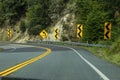 Curve on two laned highway in USA with hill on one side and many  curve road signs Royalty Free Stock Photo