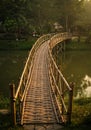 Curved Bamboo Bridge Over Tranquil River in Lush Green Setting Royalty Free Stock Photo