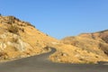 Curved black road in yellow hills