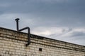 A curved chimney stack with a cap against an overcast thundersto