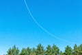 A curved contrail in the blue sky after the flight of a passenger airliner. The plane turns in the sky, the flight returns to the