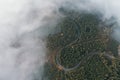 Curved country road in the colored autumn forest with fog, aerial top view Royalty Free Stock Photo