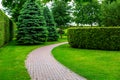 Curved crescent stone tile walkway in the backyard among green plants.