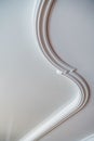 Curved decorative clay stucco relief molding on white ceiling in abstract classical style interior