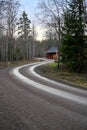 curved gravel road through forest with red barn
