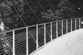 Curved metal pedestrian bridge pickets and rail with suspension cables, black and white