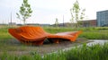 Curved orange bench in modern park setting with grass and trees Royalty Free Stock Photo
