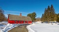 Curved road leading to red barn in Winter snow