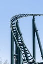 Curved Rollercoaster at a theme or amusement park empty green metal tracks and on blue sky background Royalty Free Stock Photo
