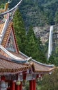 Curved roofs of colorful Chinese temple and Nachi waterfalls on the background. Wakayama. Japan