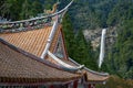 Curved roofs of colorful Chinese temple and Nachi waterfalls on the background. Wakayama. Japan