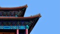 Curved roofs in traditional Chinese style with figures on the blue sky background.