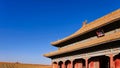 Curved roofs in traditional Chinese style with figures on the blue sky background. The Imperial Palace in Beijing