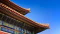 Curved roofs in traditional Chinese style with figures on the blue sky background. The Imperial Palace in Beijing