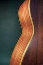 Curved side of wooden guitar on dark green background Royalty Free Stock Photo