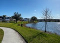 A curved sidewalk next to a lake that is a walking path in back of homes in Laureate Park